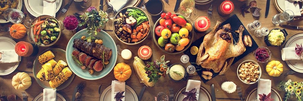 A Thanksgiving dinner spread on a table decorated with fall decorations.