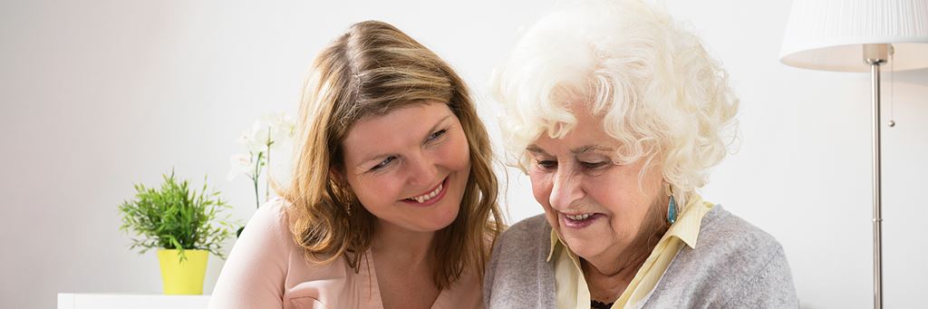 A senior woman and her daughter smile together.