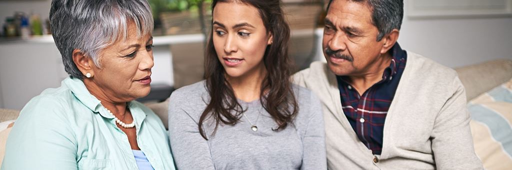 A daughter sits with her older parents.