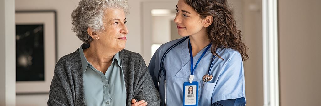 A nurse assists a senior patient with walking during a medical visit.