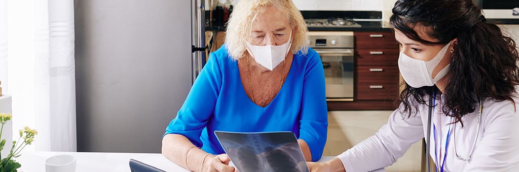 A senior speaks with a doctor about an X-ray after a medical exam.
