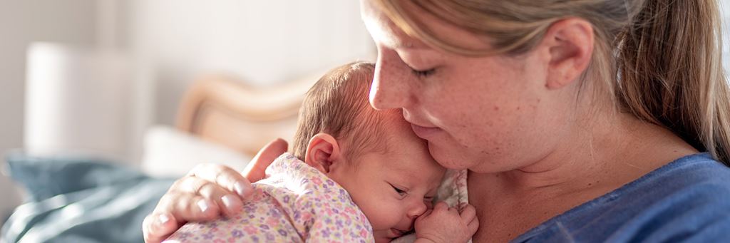 A mother holds her newborn child in her home.